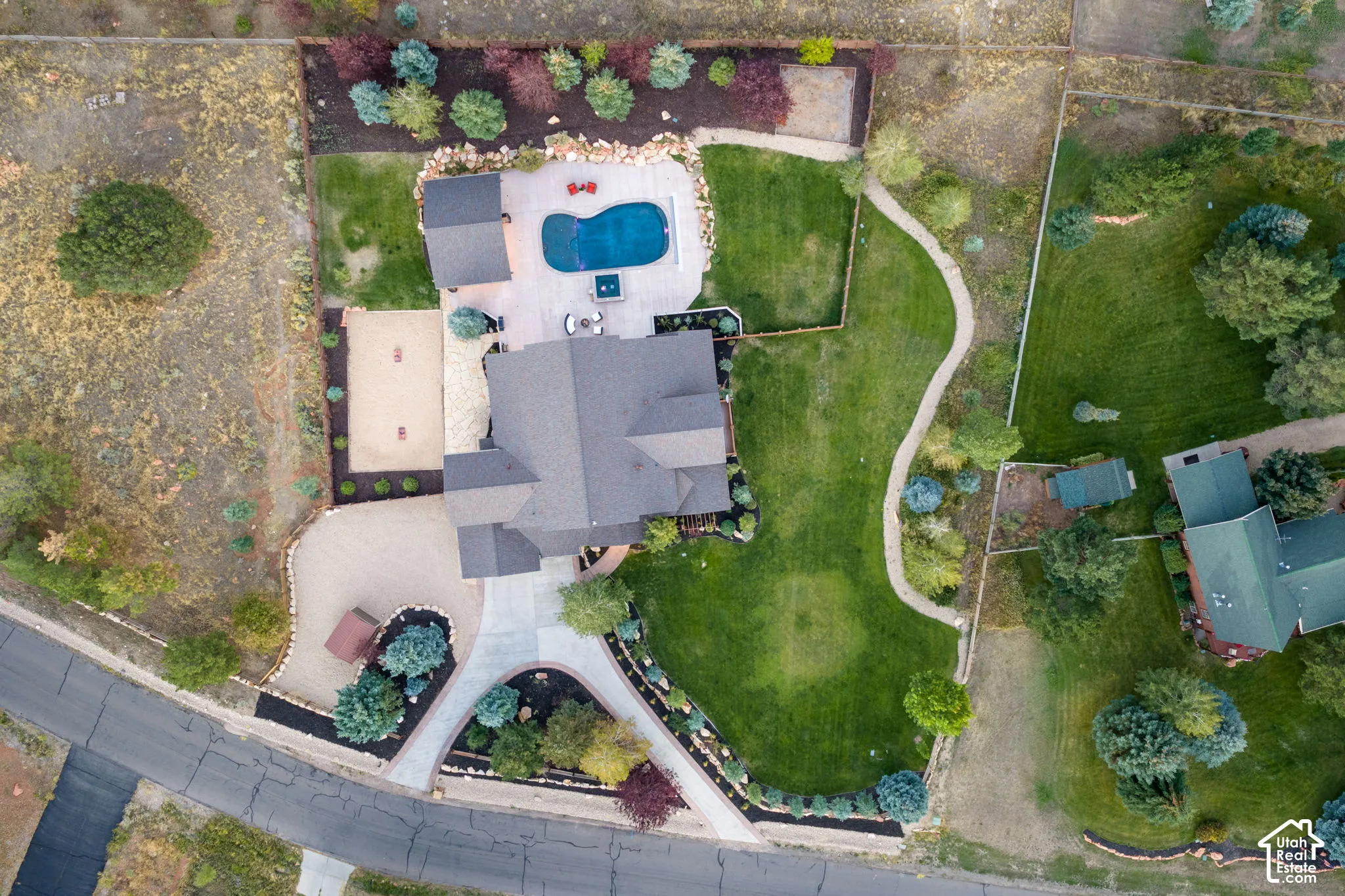 Landscaped property featuring a dark-roofed residence, a swimming pool, and a gravel driveway