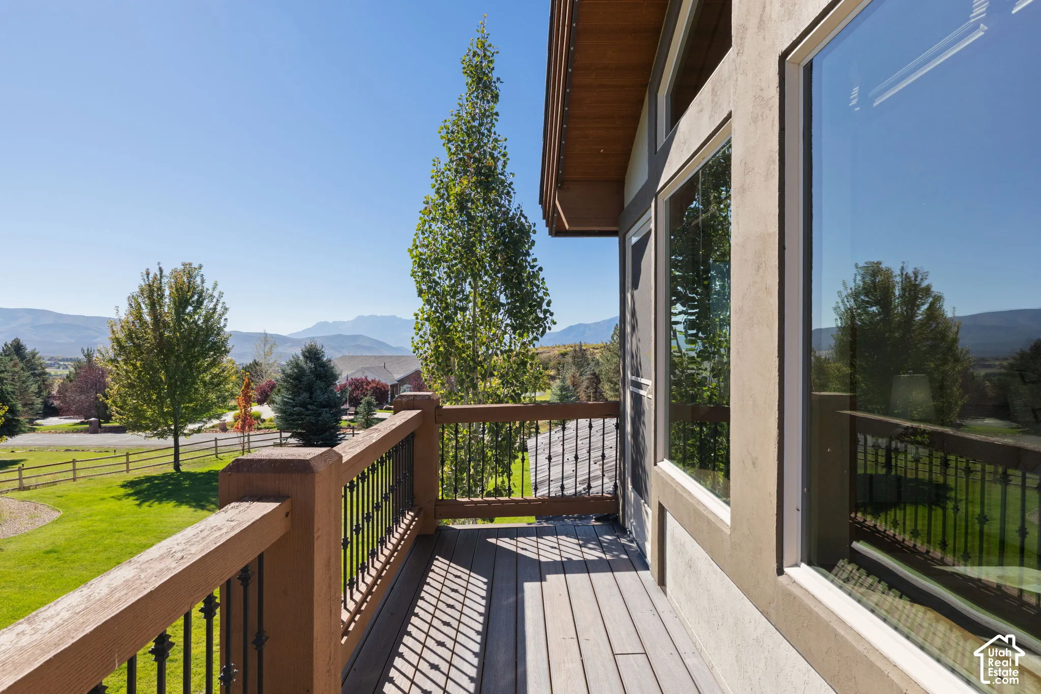 Exterior wood-finish deck with metal balusters, large windows, and a wood soffit
