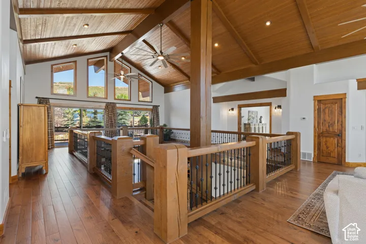 Vaulted wood-paneled ceilings with exposed beams, wood-finish flooring, and a substantial wood-and-iron railing system