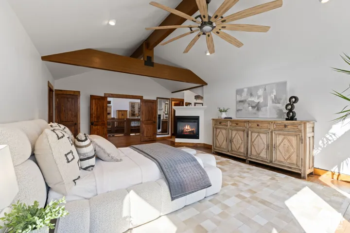 Vaulted ceiling with exposed wood beams, ceiling fan, built-in fireplace, and wood-finish flooring