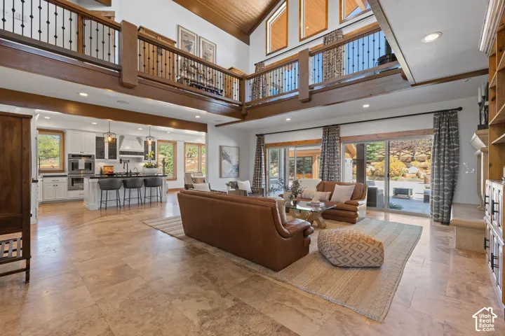 Open concept living area featuring high ceilings, exposed wooden beams, and a second-story interior balcony
