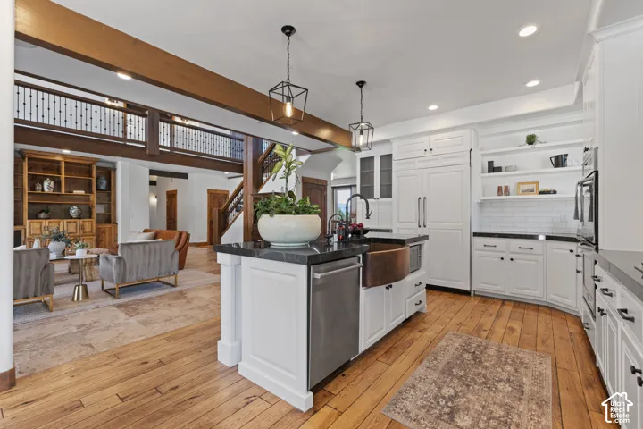 White cabinetry with dark hardware, stone countertops, wood-finish flooring, subway tile backsplash, and a copper-toned basin sink