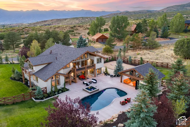 Stucco exterior with wood trim accents, multi-level patio with an integrated pool, detached covered outdoor living area, and extensive landscaping