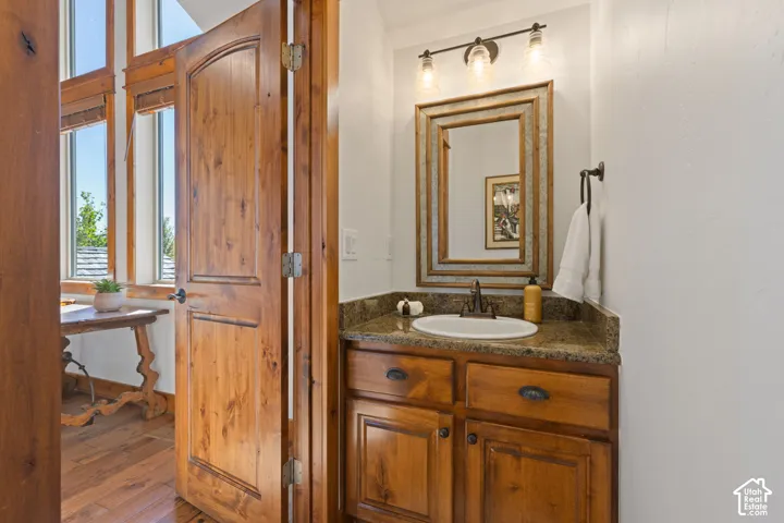 Wood-finish door with an arched top panel, coordinating wood-finish cabinetry, a built-in sink, and a stone countertop
