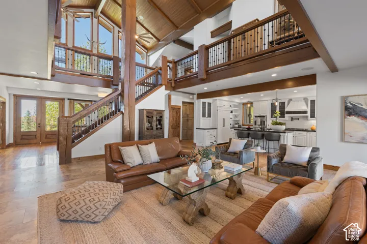 Vaulted wood-finish ceilings, an open-concept living space, a kitchen with a large island, and a prominent staircase with a wrought-iron baluster