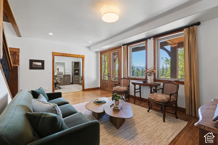 Wood-finish flooring throughout, exposed wood beams, and multiple windows providing outdoor scenery