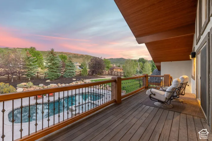 Spacious outdoor deck with wood-finish flooring, iron railings, and an oval swimming pool