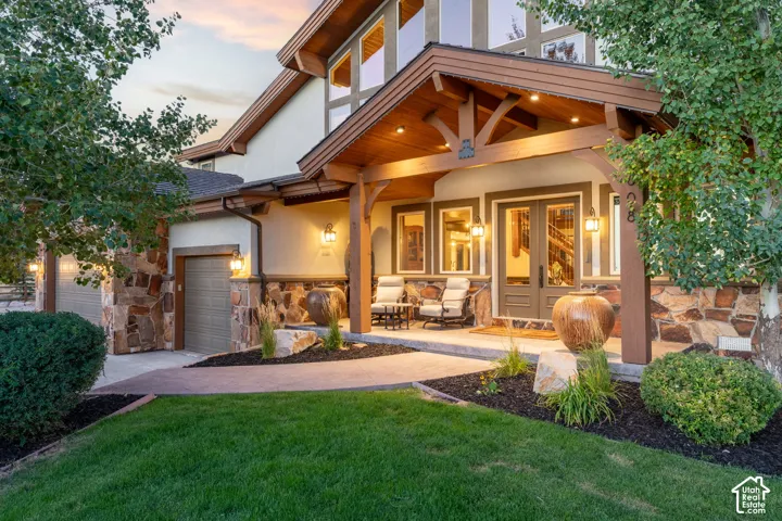 Stone and stucco exterior with multiple garage bays, covered entry, double entry doors, and professional landscaping