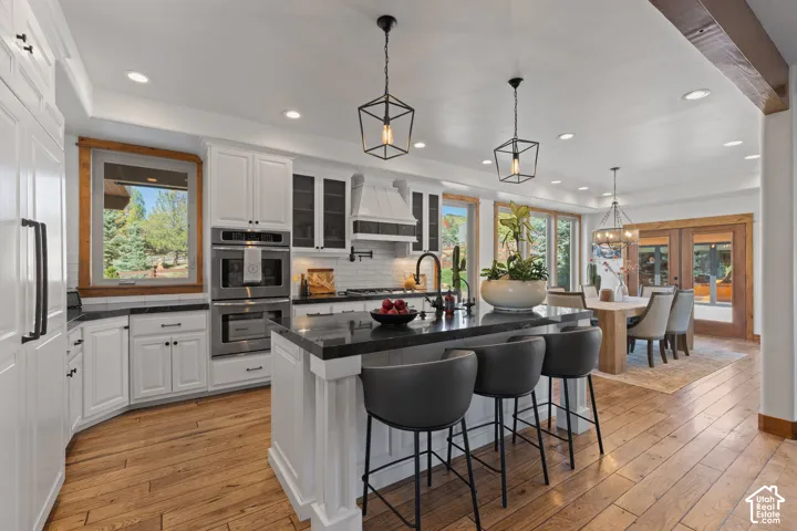 Gourmet kitchen with wood-finish flooring, white cabinetry, dark countertops, and stainless steel double ovens