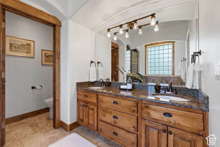 Double vanity with granite countertop, wood cabinetry, and dual undermount sinks