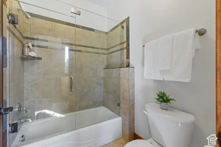 Bathtub with a glass shower enclosure, full tile surround, and a wall-mounted showerhead