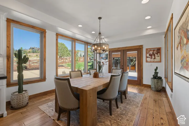 Hardwood flooring, recessed ceiling lighting, wood-trimmed windows, a multi-light chandelier, and double paneled doors