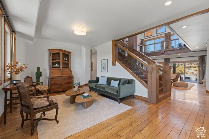 Hardwood flooring throughout, a grand wooden staircase, an open balcony, and large windows providing ample natural light