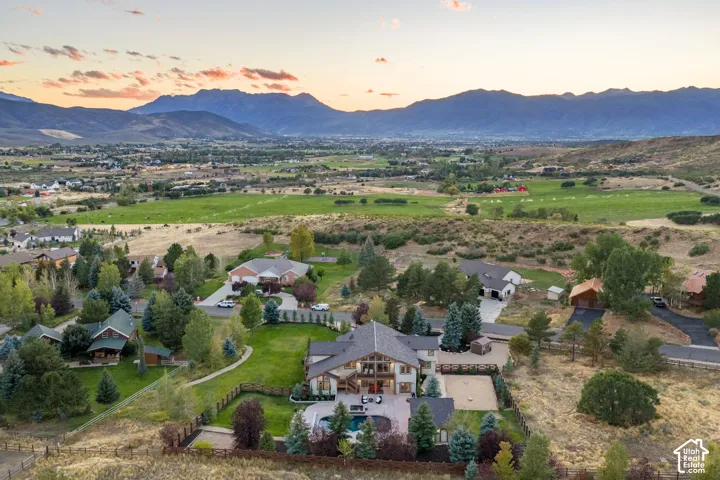 Expansive property featuring a multi-level residence, swimming pool, manicured lawn, and mature trees, set against a mountain backdrop
