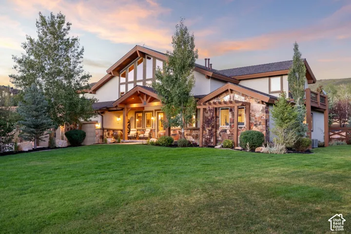 Exterior featuring stone and stucco finishes, a covered front porch, large gable windows, and a pergola with climbing greenery