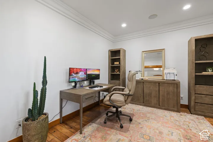 Hardwood-style flooring, white walls, recessed ceiling lights, and crown molding