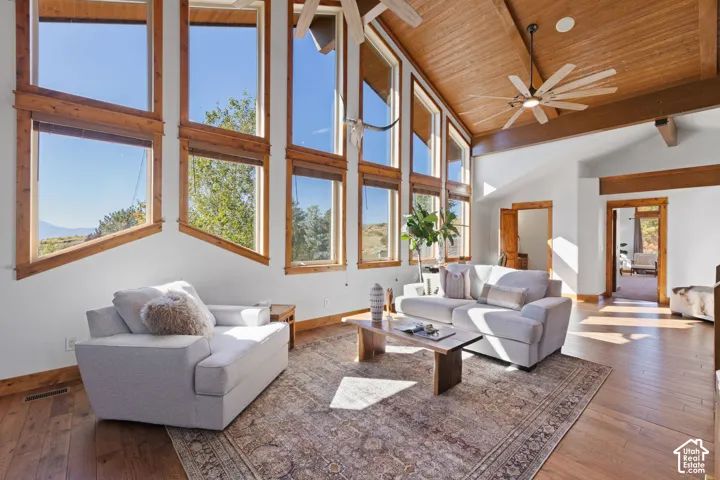 Vaulted wood-paneled ceiling with exposed beams, hardwood flooring, expansive windows, and wood-trimmed doorways