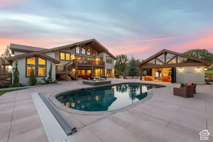 Expansive outdoor entertaining area with a freeform swimming pool, integrated fire pit, and extensive paved decking