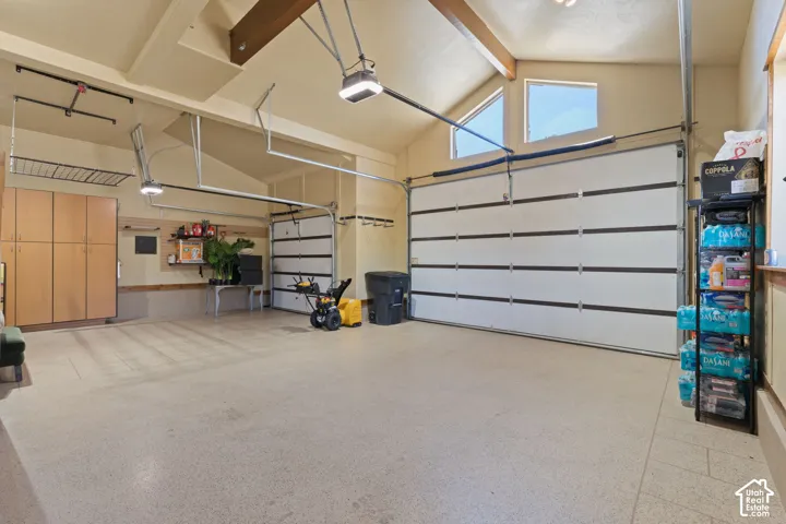 Two white garage doors, vaulted ceiling with exposed wood beams, and built-in cabinetry