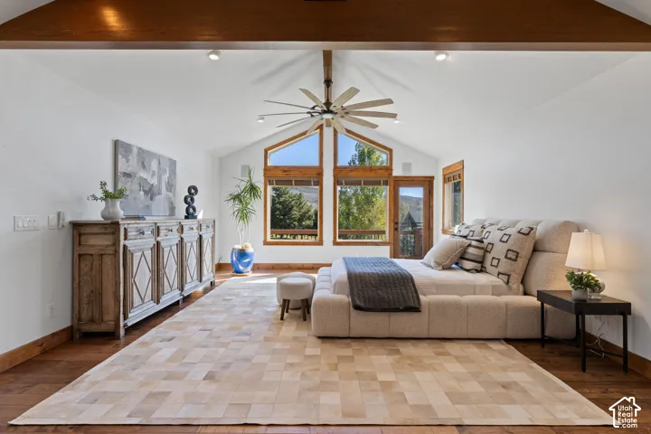 Vaulted ceilings with exposed wood beams, wood-finish flooring, a ceiling fan, and large windows with wood frames