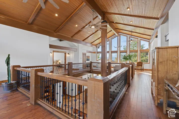 Vaulted wood-paneled ceiling with exposed beams, wood-finish flooring, custom wood and wrought iron railings, and multiple large windows