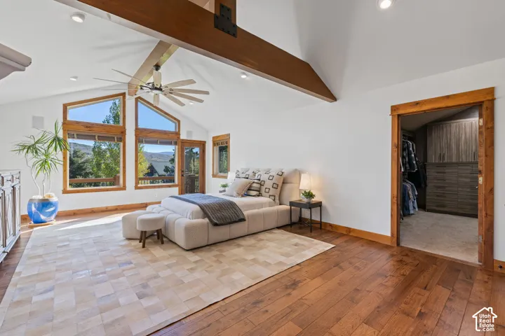 Vaulted ceilings with exposed wood beams, hardwood flooring, and large windows with wood frames