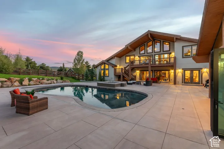 Expansive patio featuring a freeform swimming pool and integrated fire pit