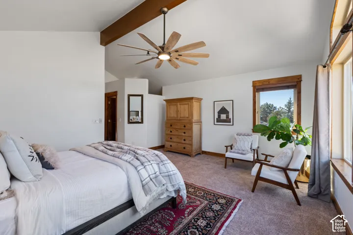 Vaulted ceiling with wood beam accents, ceiling fan with wood-finish blades, and multiple windows with wood trim