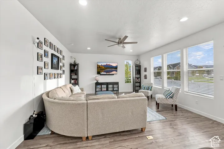Spacious living area featuring wood-finish flooring, recessed lighting, and a ceiling fan