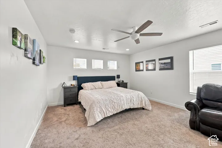 Recessed lighting, ceiling fan, multiple windows with blinds, and neutral-toned carpeting