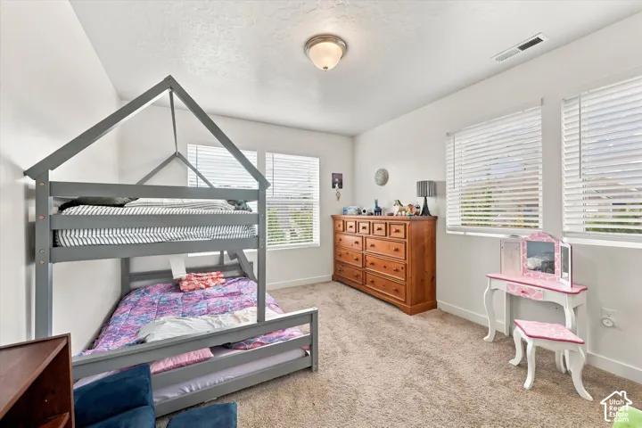 Carpeted flooring, two windows with blinds, and an overhead light fixture