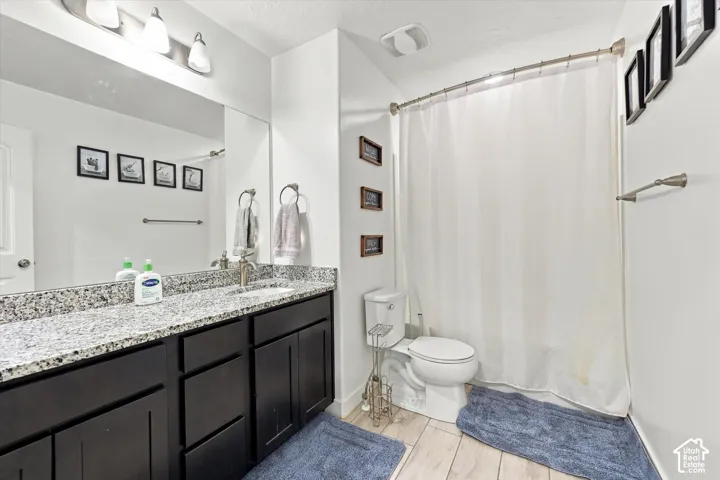Vanity with granite countertop, dark wood-finish cabinetry, and brushed nickel fixtures