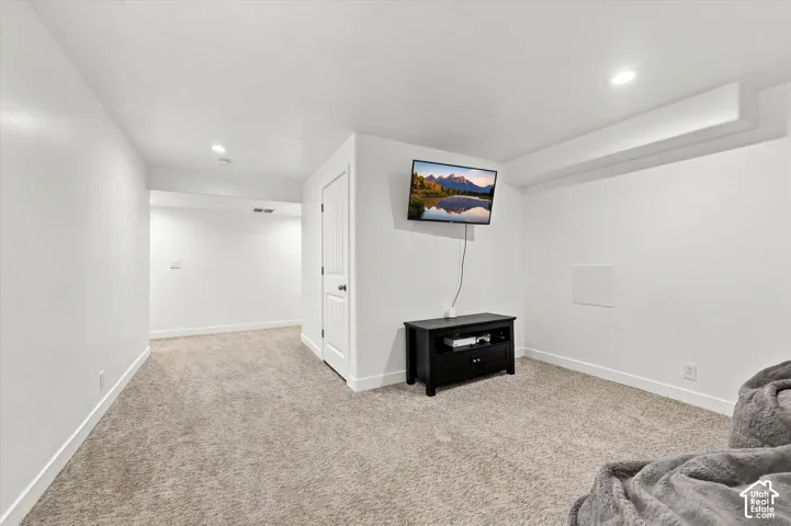Carpeted room with recessed lighting and a white paneled door