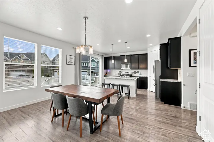 Wood-finish flooring, recessed lighting, and a modern chandelier illuminate this space