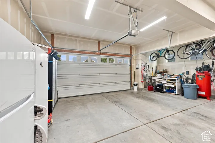 Spacious garage with concrete flooring, automatic garage door opener, overhead fluorescent lighting, and built-in shelving