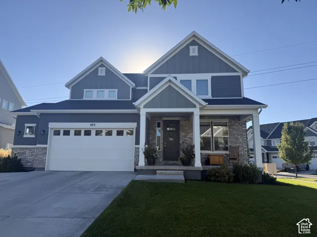 Two-story facade with stone and siding accents, prominent gabled rooflines, two-car garage with transom windows, covered front porch, and manicured lawn