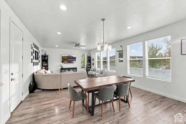 Open-concept living space with wood-finish flooring, multiple windows, recessed lighting, and a ceiling fan