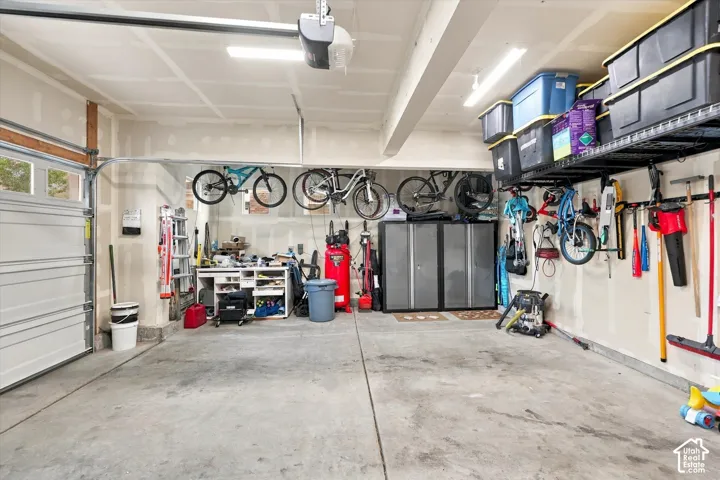 Spacious garage featuring a concrete floor, overhead storage racks, and wall-mounted organization systems