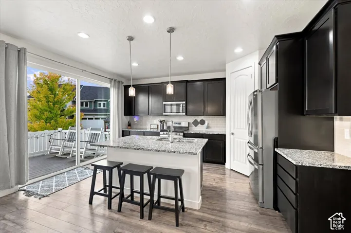 Kitchen featuring dark cabinetry, light countertops, wood-finish flooring, recessed lighting, and a sliding glass door opening to a deck