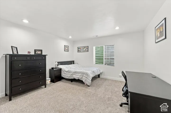 Recessed ceiling lighting, a window with horizontal blinds, neutral wall paint, and carpeted flooring