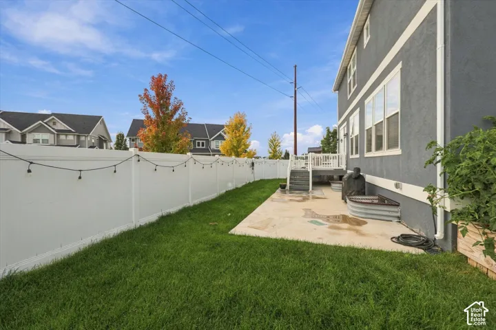 Private backyard featuring a concrete patio, white vinyl fencing, and a manicured lawn