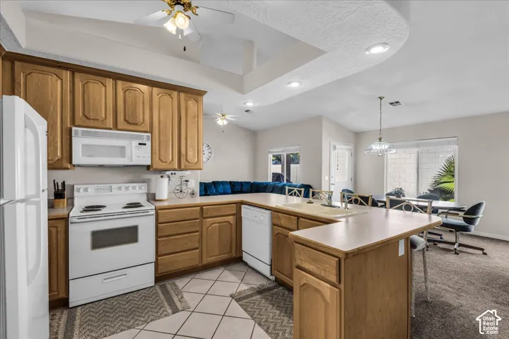 Kitchen featuring wood cabinetry, white appliances, and tiled flooring