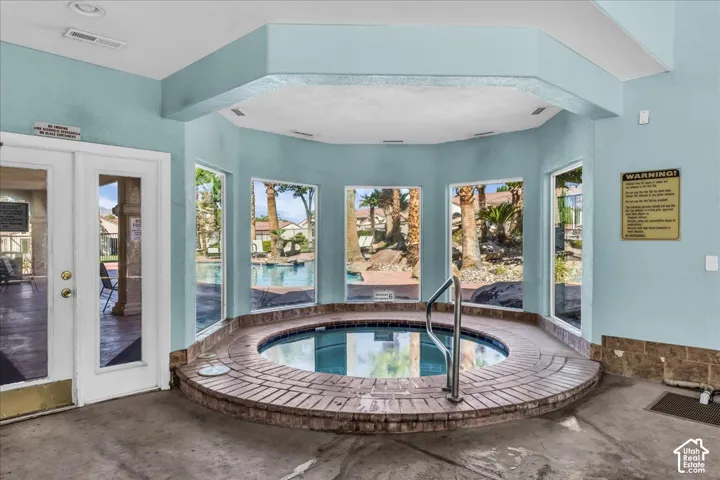 Indoor spa with brick-finish surround, multiple windows, and direct outdoor access through glass-paneled double doors