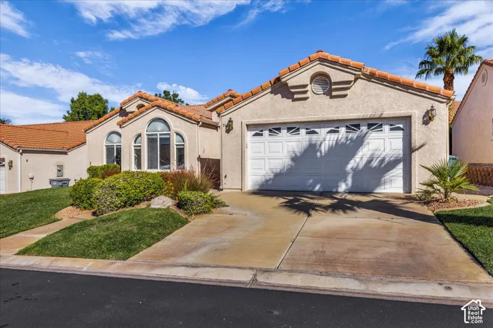 Stucco exterior with a terracotta tile roof, arched windows, and an integrated garage
