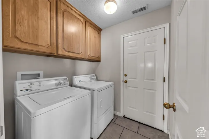 Laundry area featuring wood cabinetry, tile flooring, and a paneled door