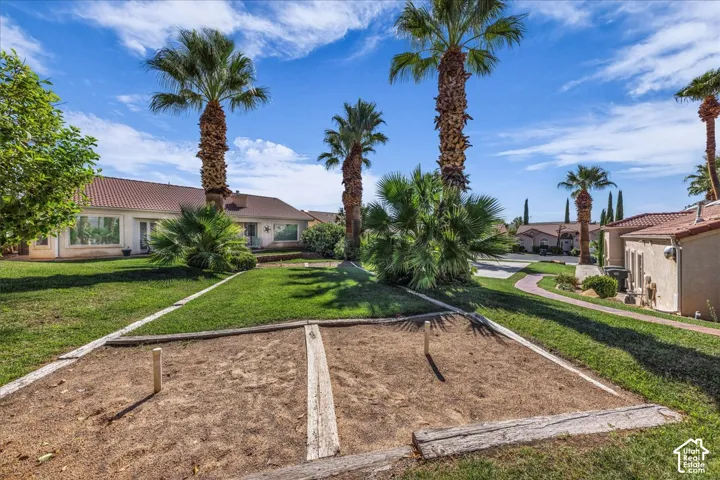 Expansive green lawn featuring a horseshoe pit, mature palm trees, and a paved pathway