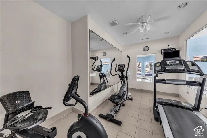 Tiled flooring with a full-wall mirror and a ceiling fan with integrated lighting