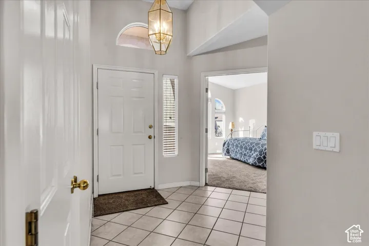 Vaulted entry featuring a decorative pendant light fixture, arched transom window, and tile flooring