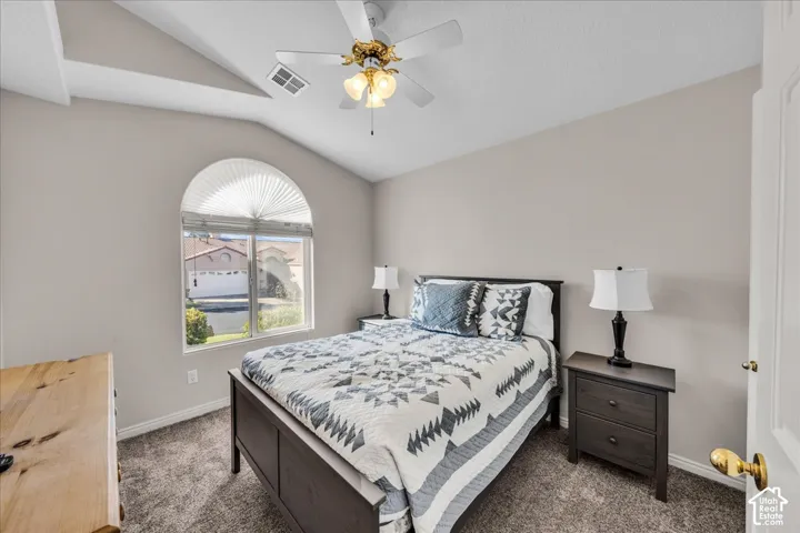 Vaulted ceiling with an arched window, ceiling fan, and carpeted flooring