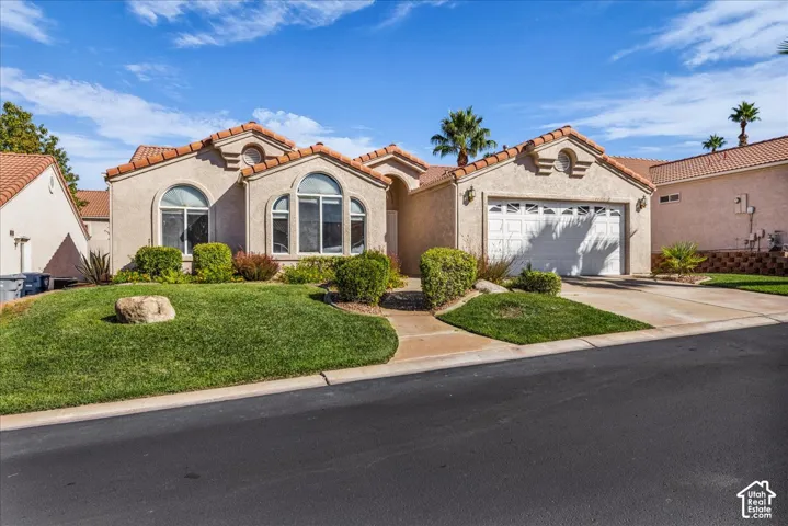 Stucco exterior with arched windows, a two-car garage, and a tile roof